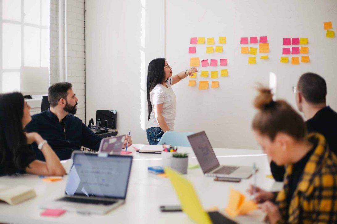 Professionelles Team in einer agilen Workshop- oder Planungssitzung mit bunten Haftnotizen an einer Wand.