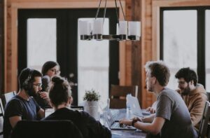 Mehrere Personen arbeiten gemeinsam mit Laptops an einem Tisch